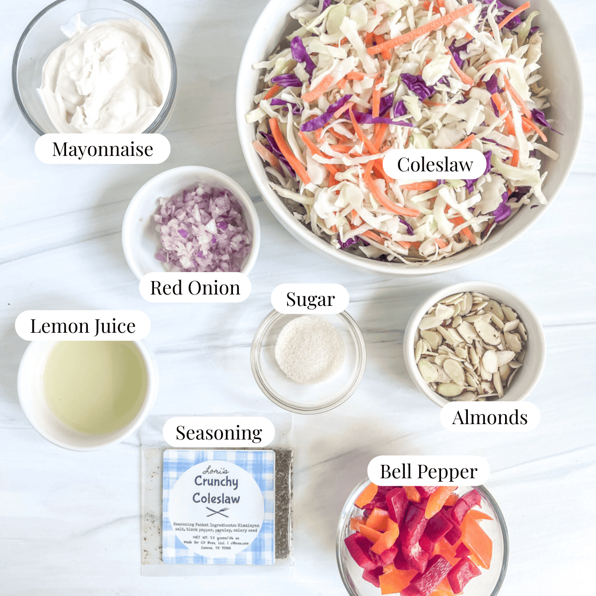 Ingredient picture with a bowl of mayonnaise, bowl of lemon juice, bowl of sugar, bowl of almonds, bowl of chopped bell pepper, bowl of coleslaw, seasoning packet