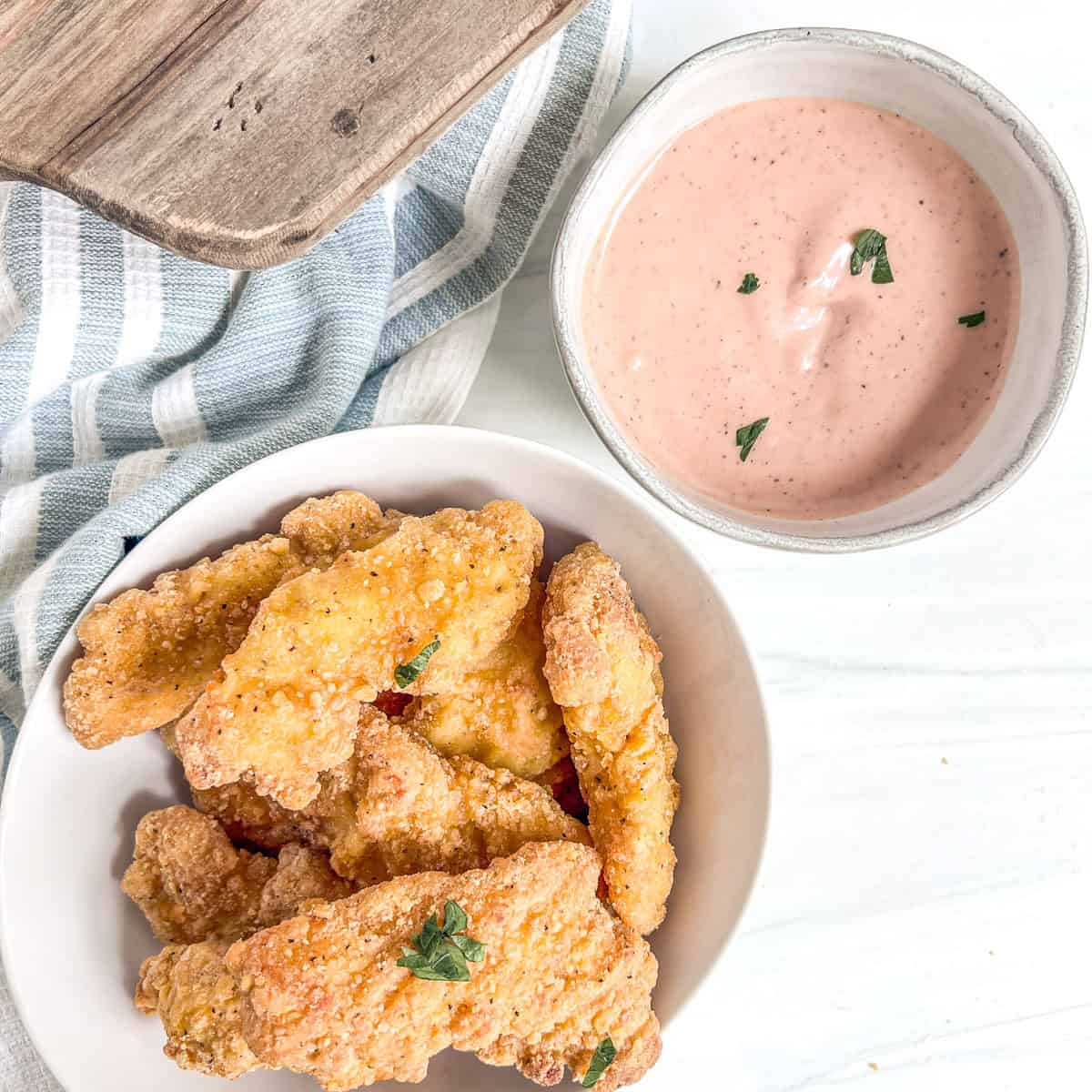 bowl of chicken tenders and a small bowl of chicken dipping sauce