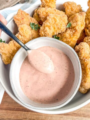 bowl of dipping sauce with a spoonful of the sauce and tenders around the sauce
