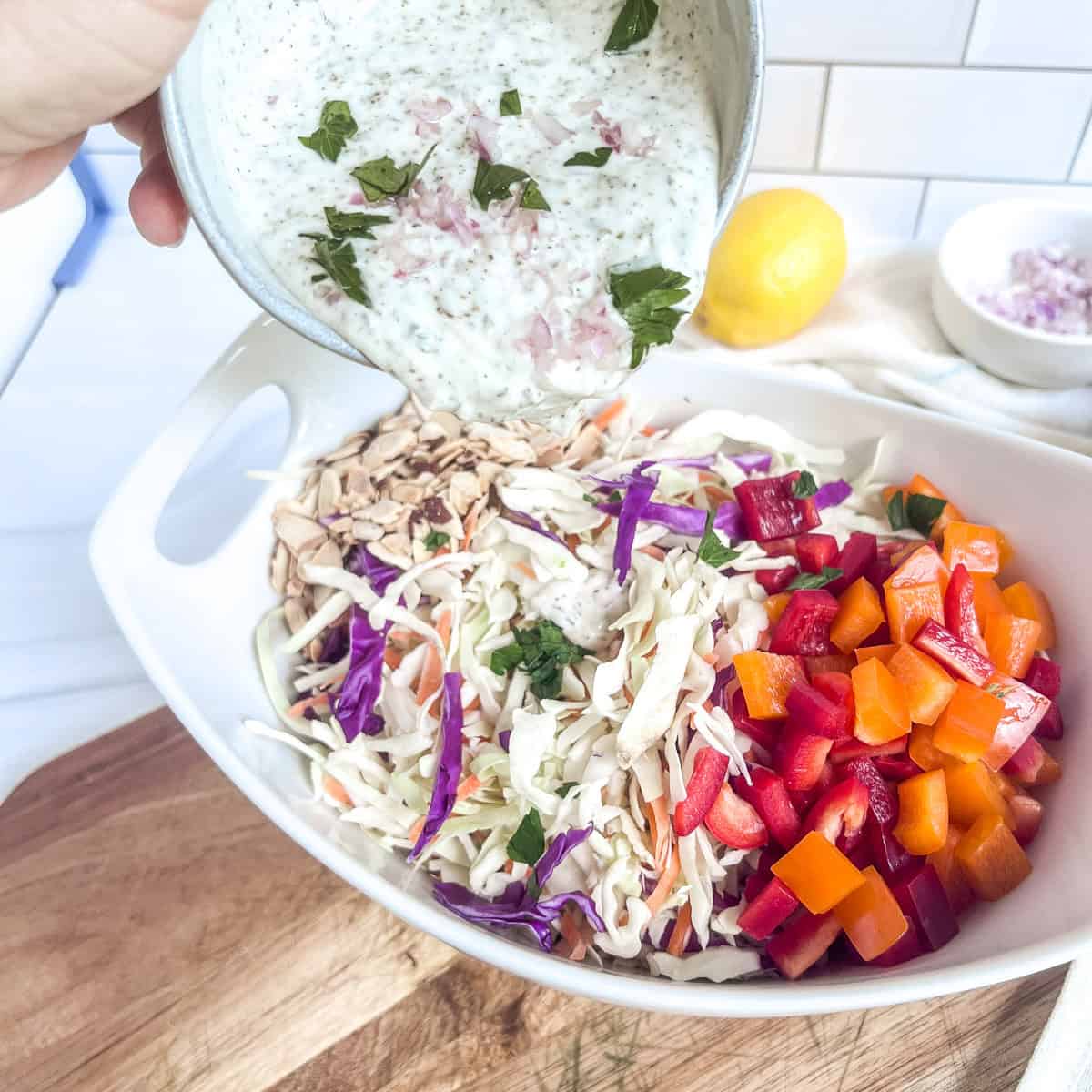 bowl pouring dressing over coleslaw in a bowl