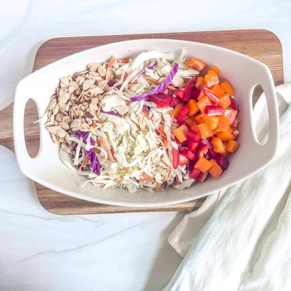 bowl with chopped cabbage and toasted sliced almonds, and chopped red and orange peppers