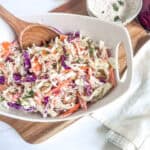 coleslaw in a white bowl with a spoon in it