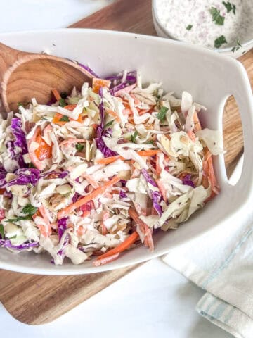 coleslaw in a white bowl with a spoon in it