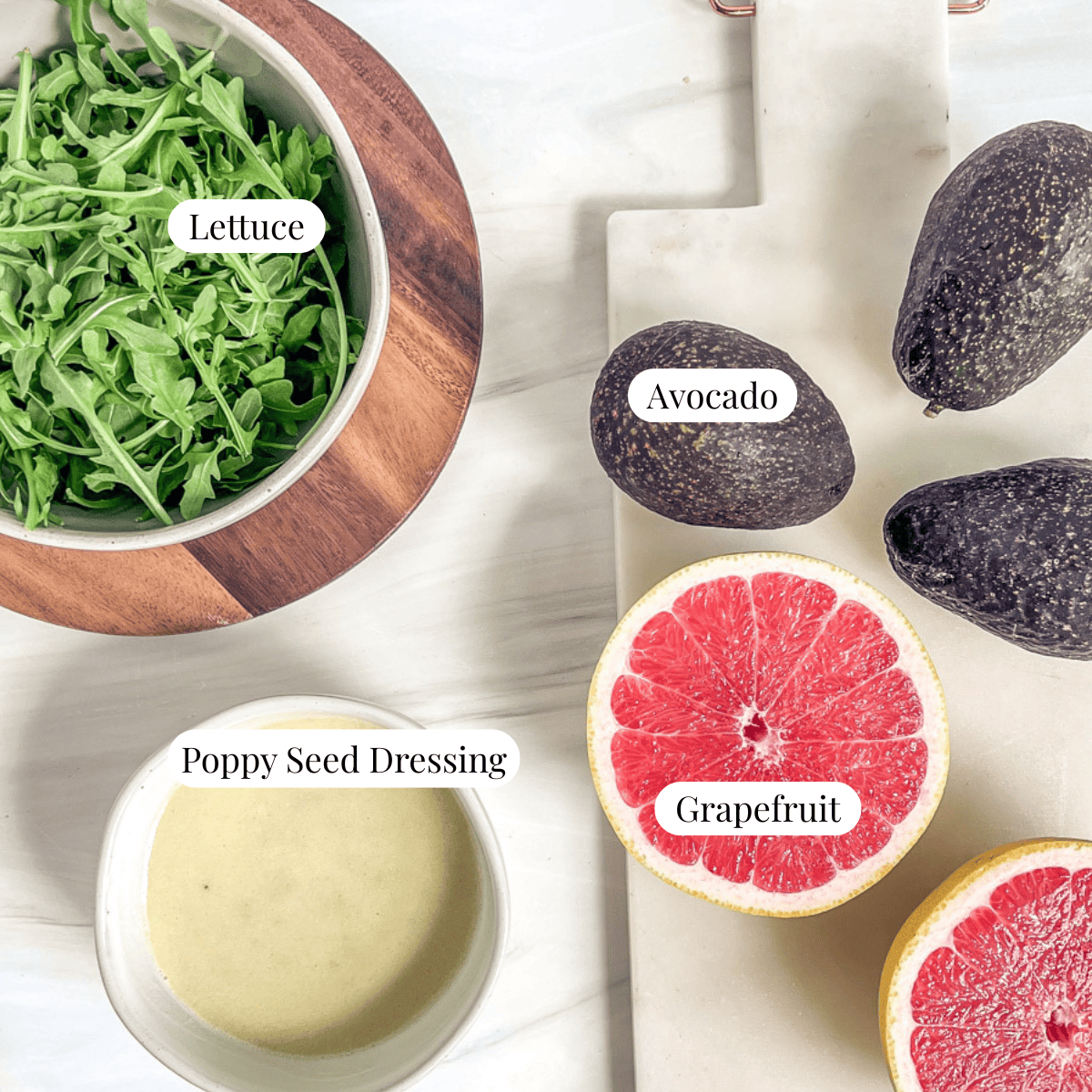 bowl of arugula salad, bowl of poppy seed dressing, grapefruit cut in half, avocados