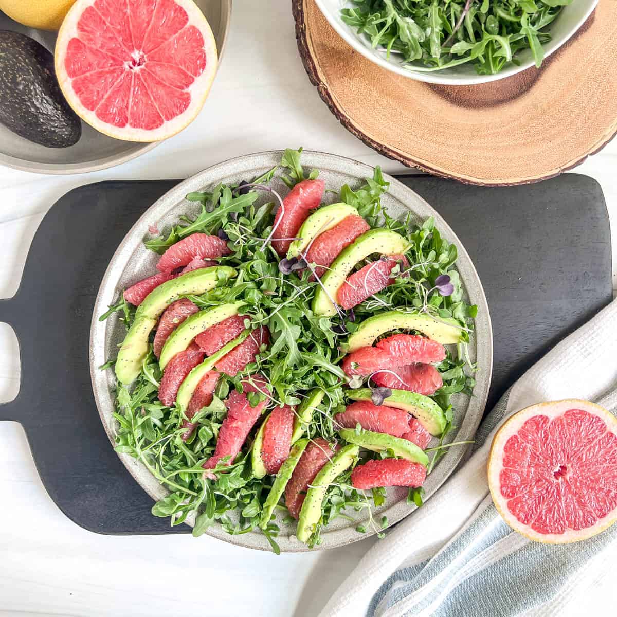 plate of grapefruit and avocado slices on a bed of lettuce with grapefruit halves to the side
