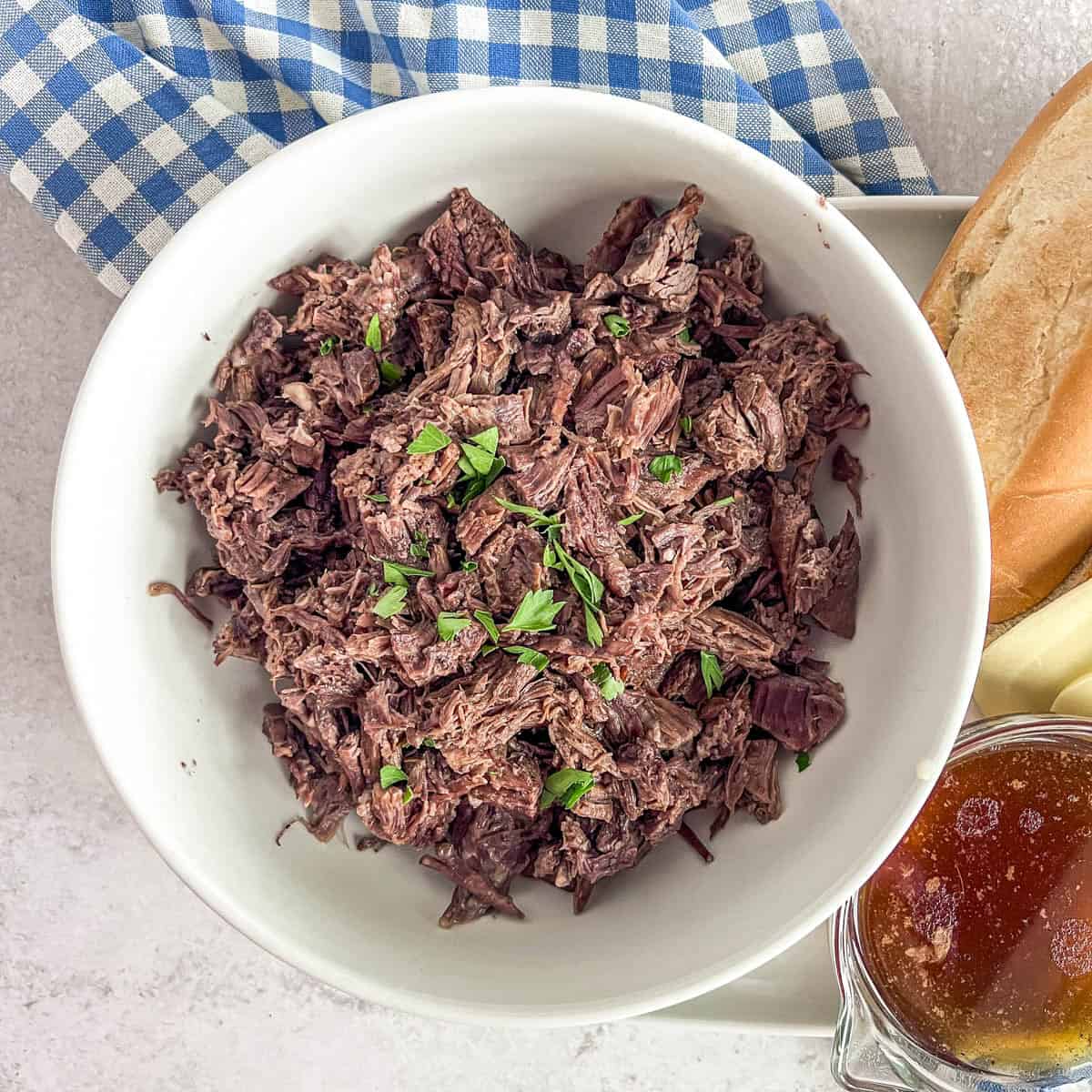 Slow Cooker Pot roast chopped roast in a bowl with juice in a bowl to the side