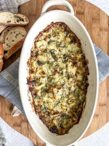 Hot spinach dip baked in a dish on a cutting board