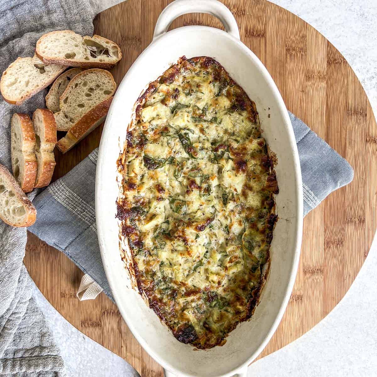 Hot spinach dip baked in a dish on a cutting board