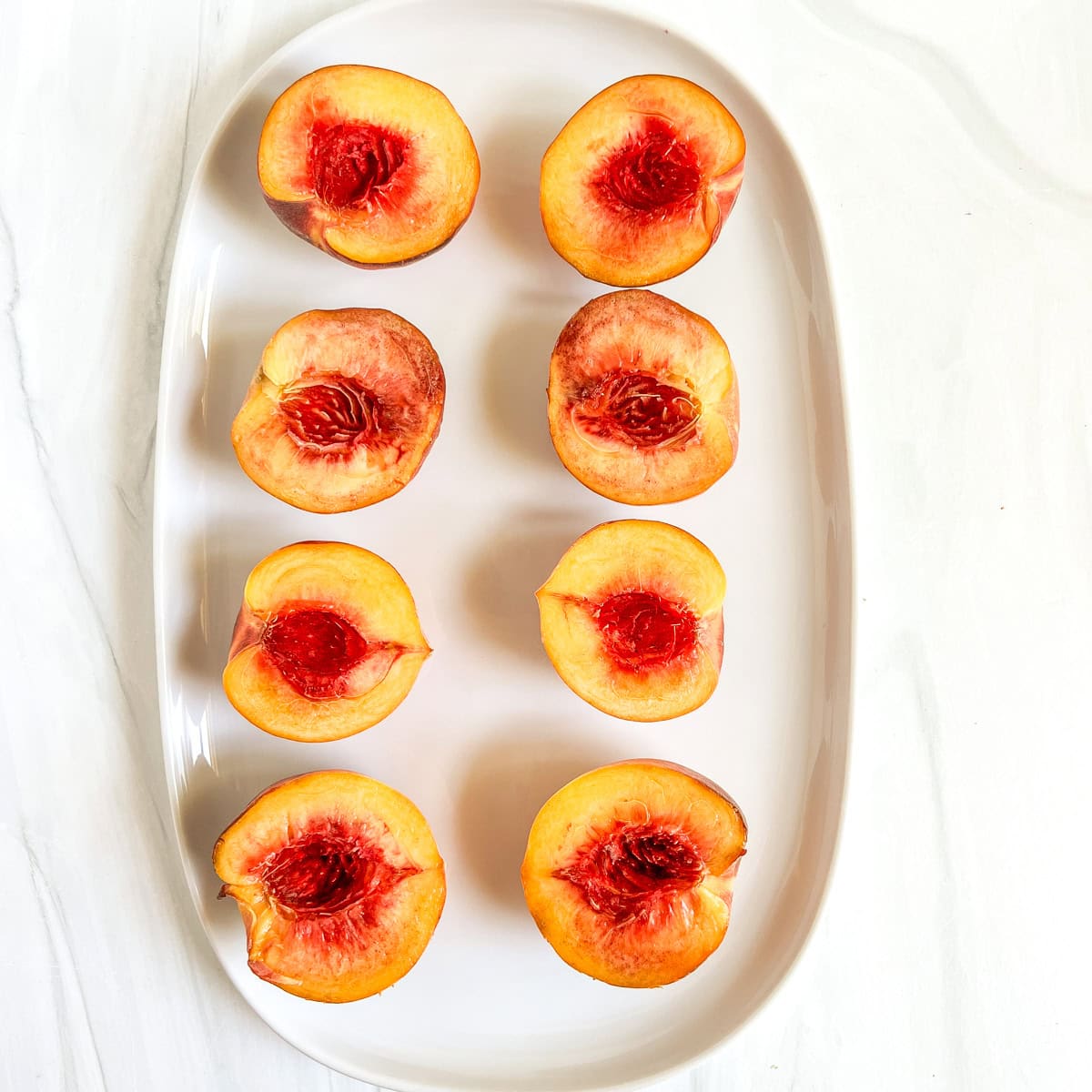 baked peaches halves on a white platter