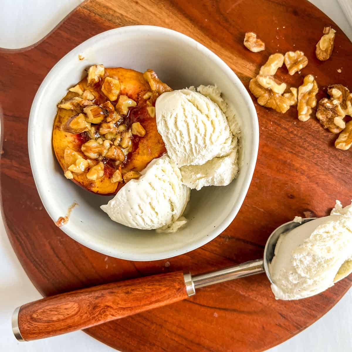 baked peaches in white bowl with ice cream