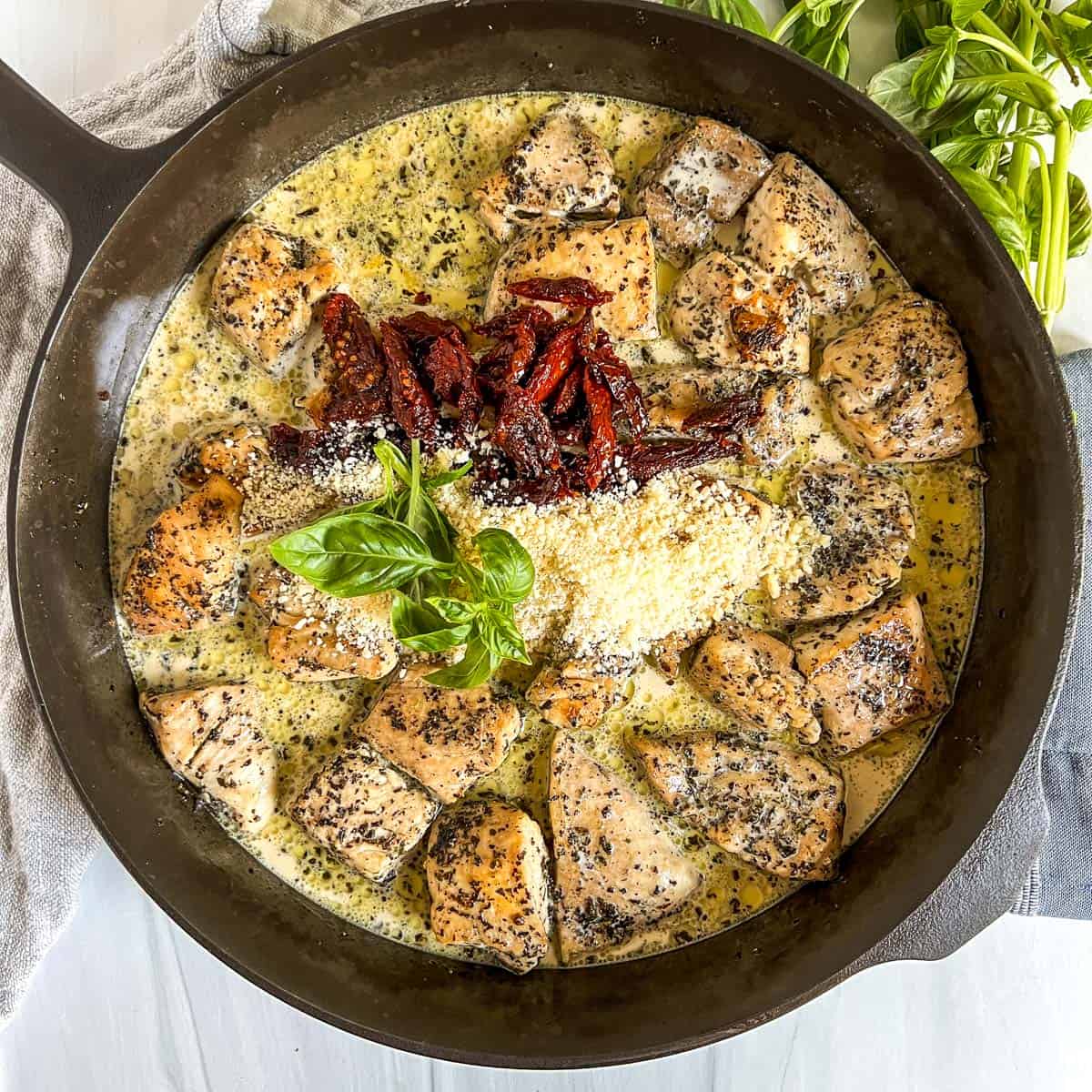 Easy Marry Me Chicken Recipe cooked chicken, cream sauce, sun dried tomatoes, parmesan cheese, basil in a cast iron skillet