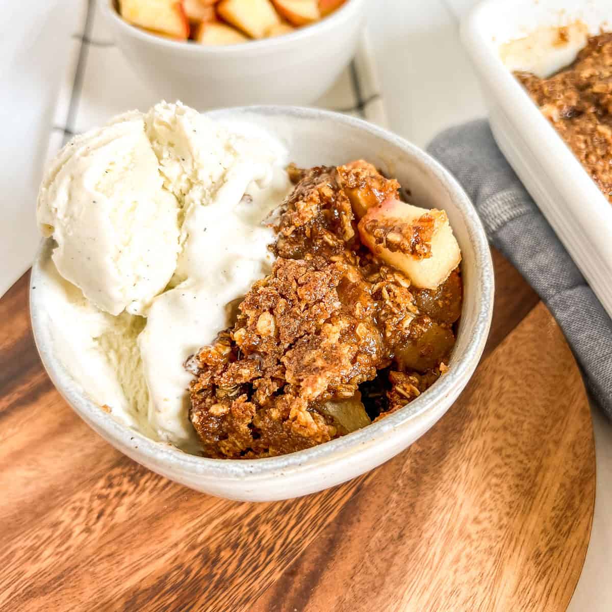 baked apple dessert with ice cream in a white bowl