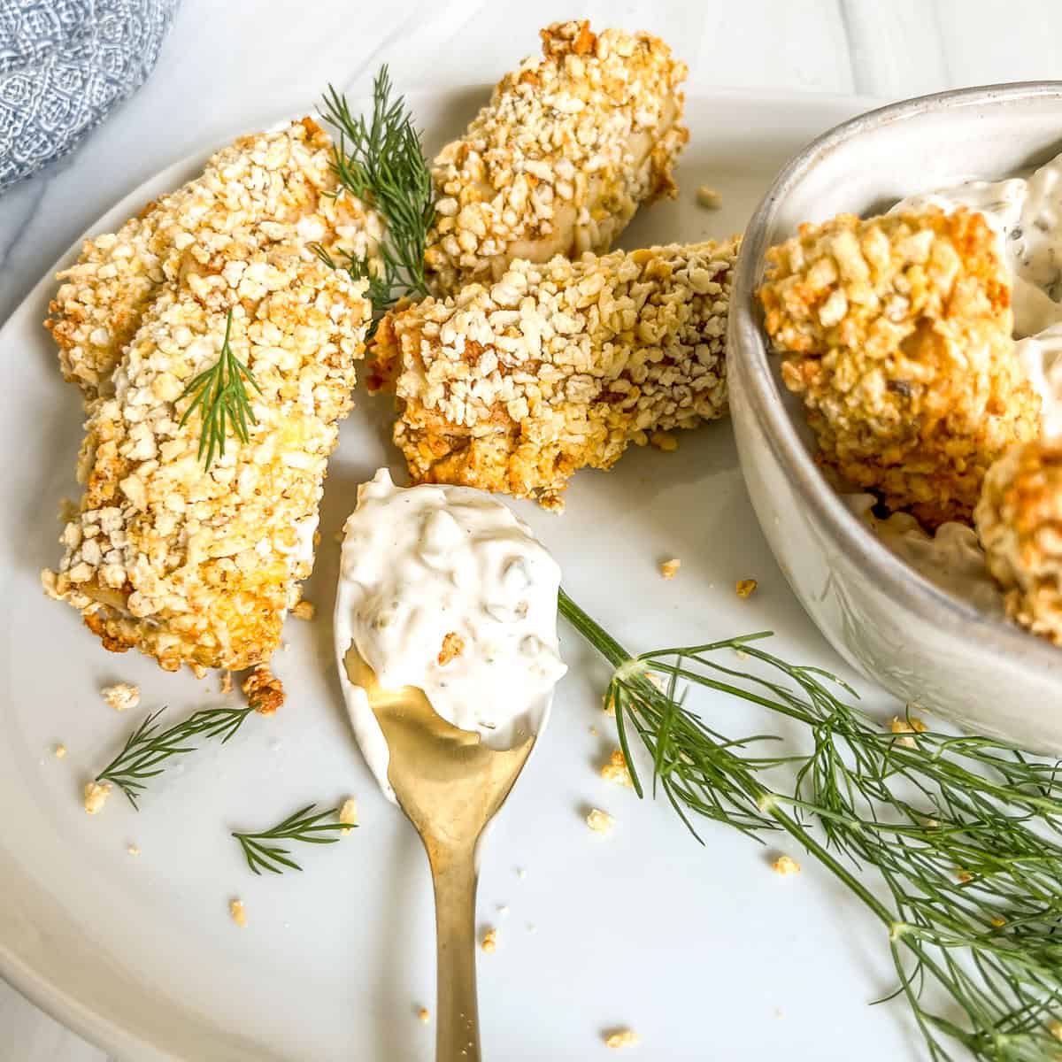crispy fish sticks with a spoon of tartar sauce