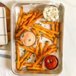 sweet potato fries on a baking sheet with different sauces