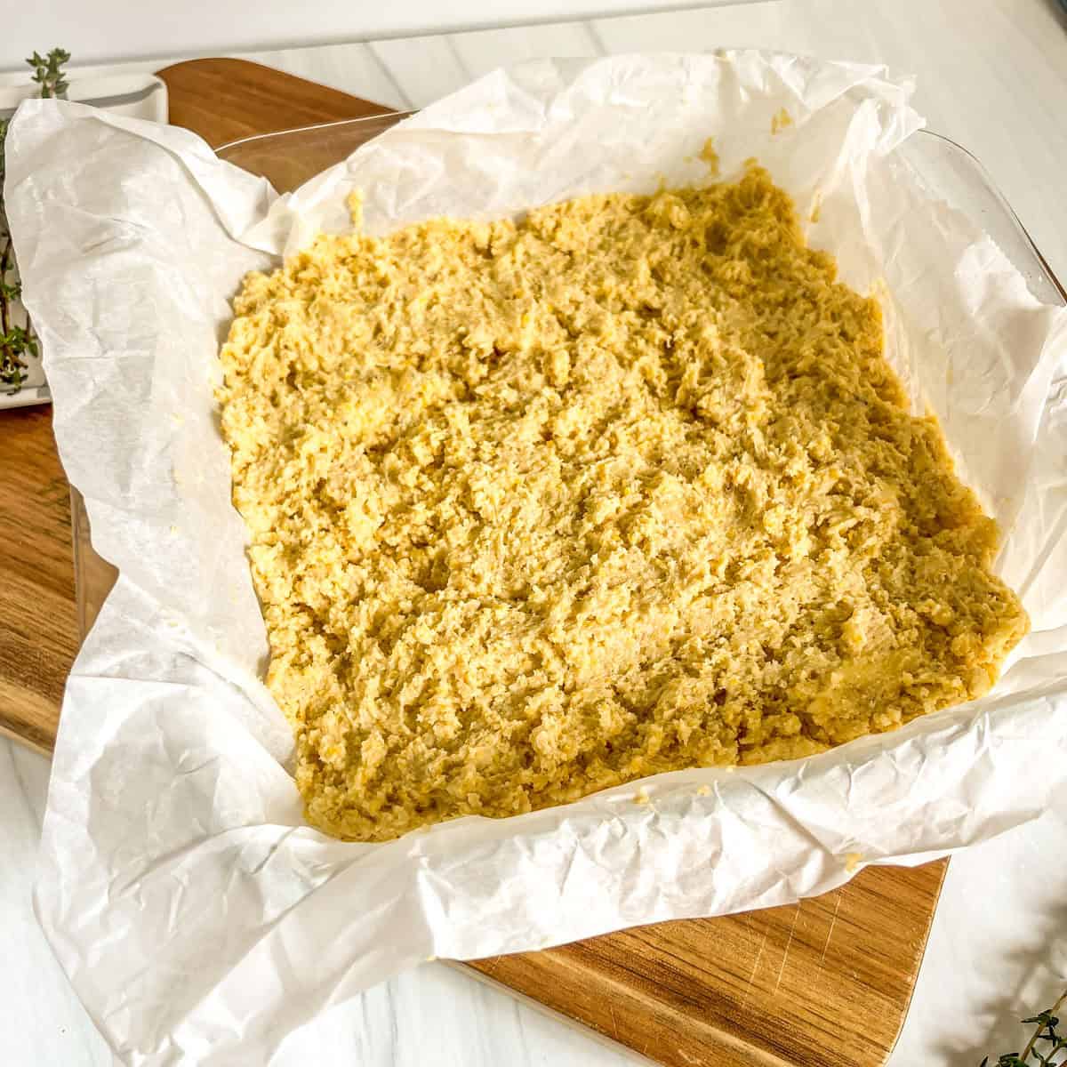 cornbread batter in a glass dish with parchment paper