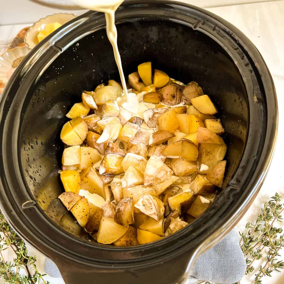 pieces of potato in a slow cooker with cream