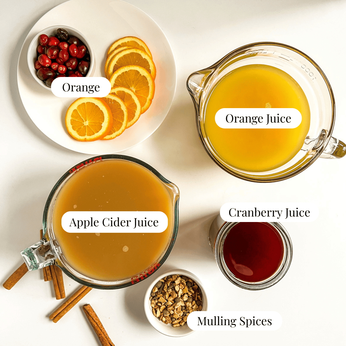 juices in bowls, orange slices, mulling spices, and cranberries in separate bowls