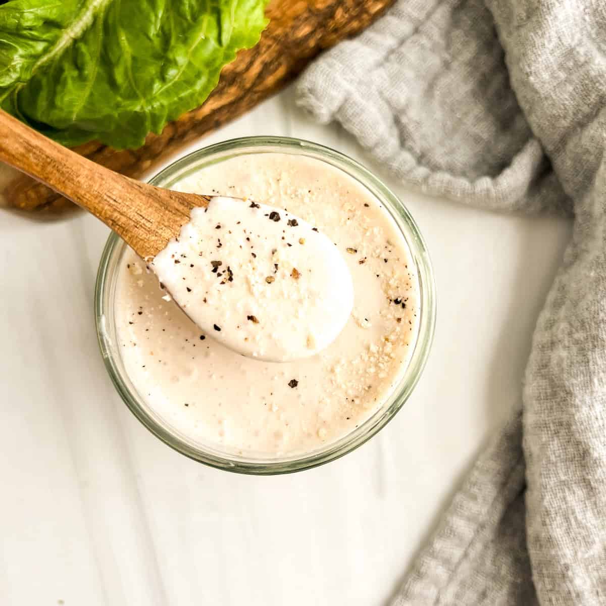 caesar salad dressing with wood spoon in jar